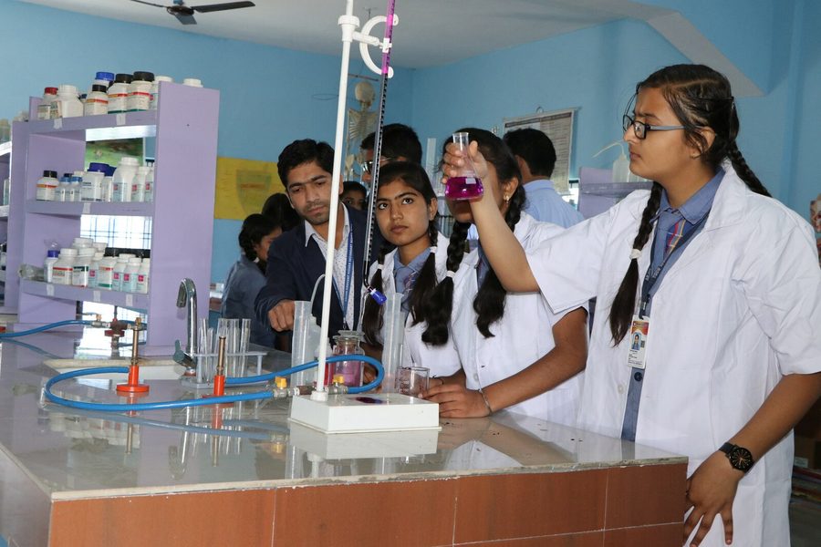 Students in lab coats running an experiment at the chemistry laboratory bench